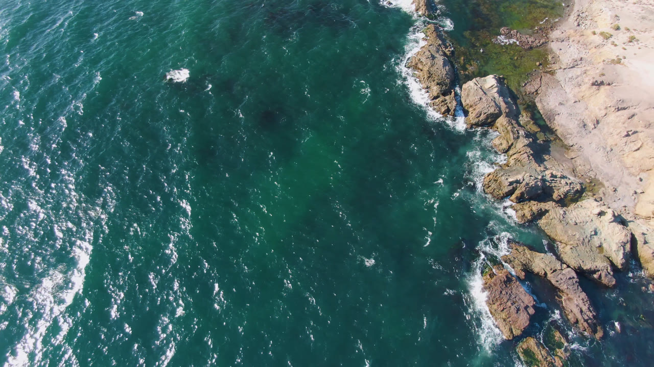 Top-down coast with teal water and rock outcrops