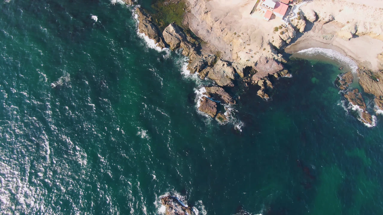 Rocky point and dark teal water with small white wave breaks.