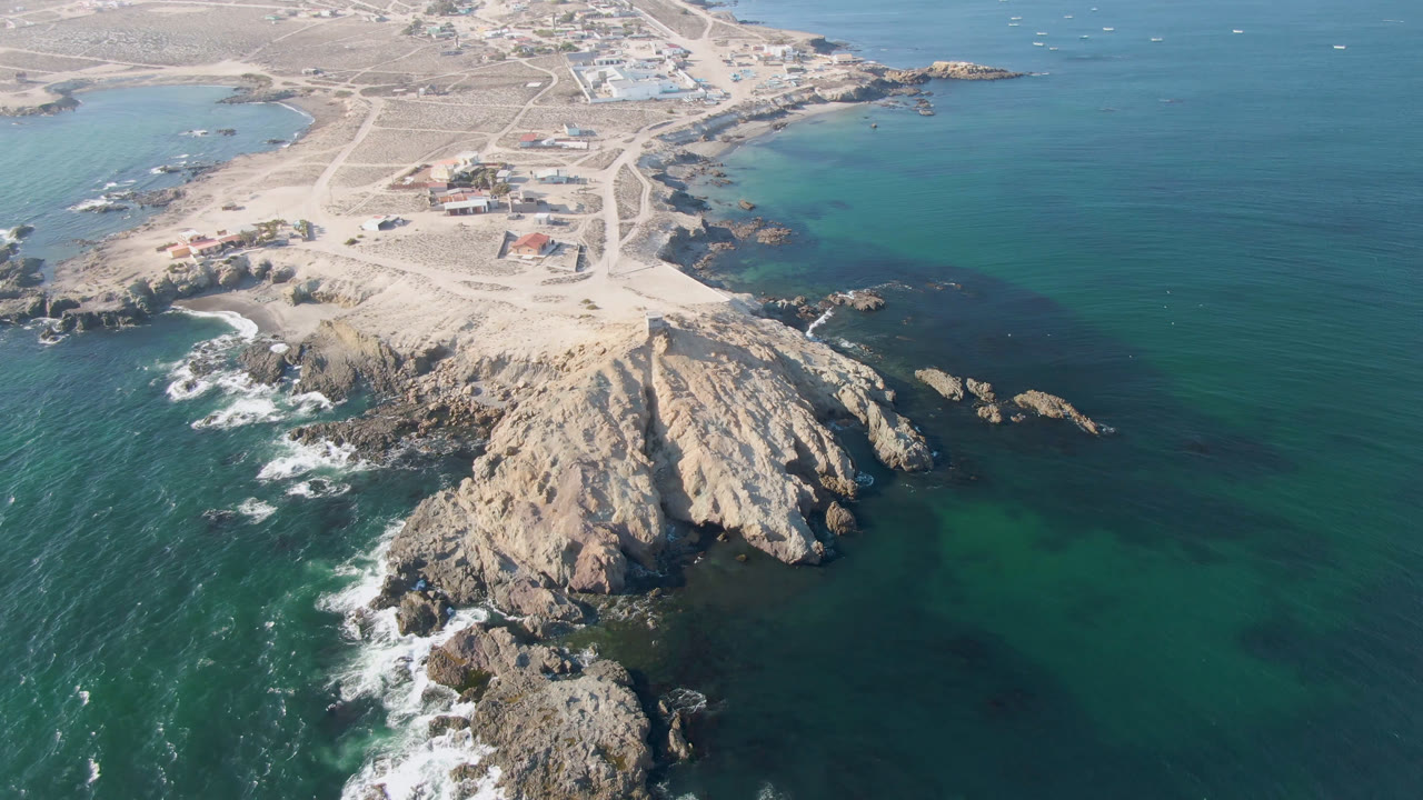 Aerial coastline with rocky headland, sandy land, and open blue ocean
