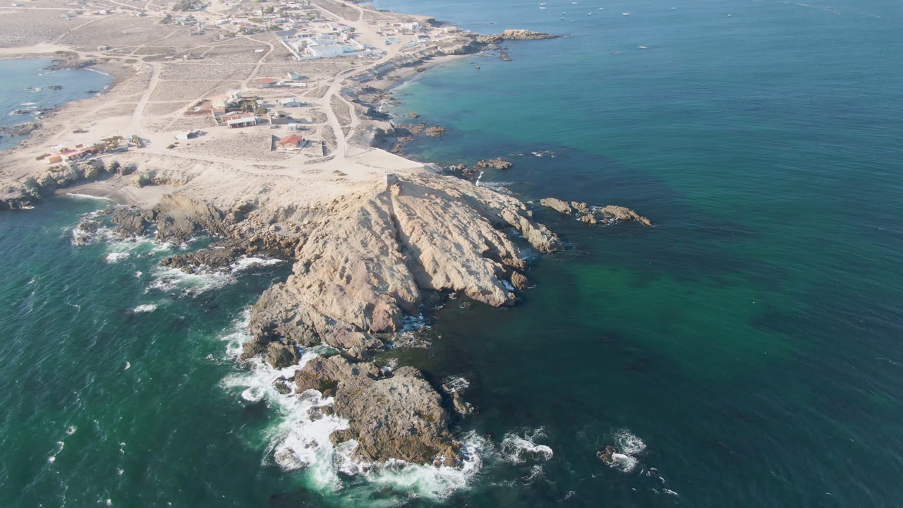 Rocky coastal point and offshore rocks surrounded by turquoise water.