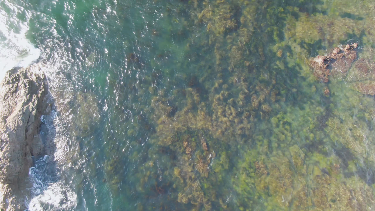 Overhead view of rocks and patterned shallow ocean water.