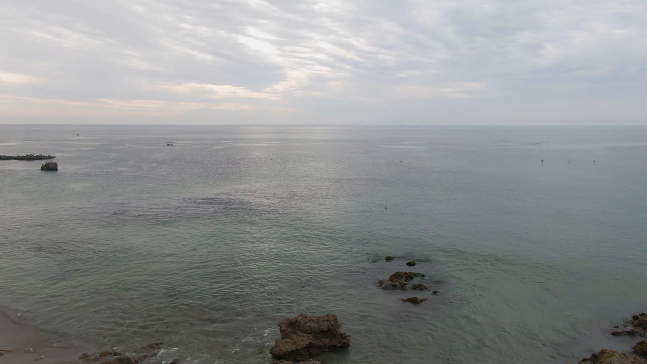 Aerial view of calm water, shoreline rocks, and a small offshore boat.