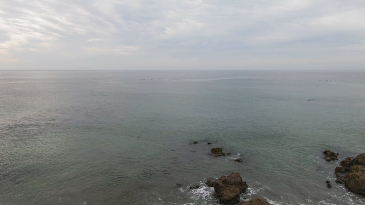 Aerial ocean view with rocks below a cloudy sky