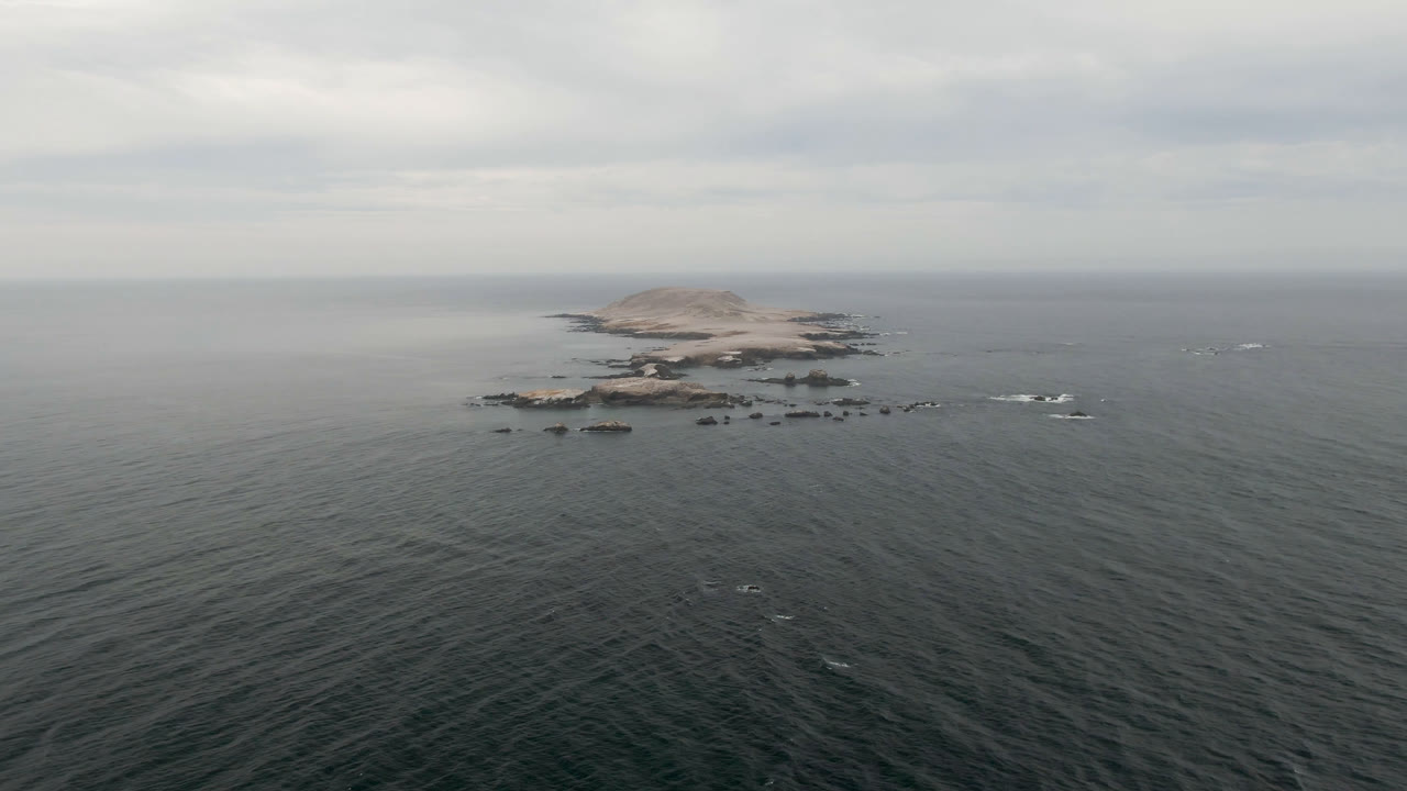 Rocky island and scattered surf in open ocean