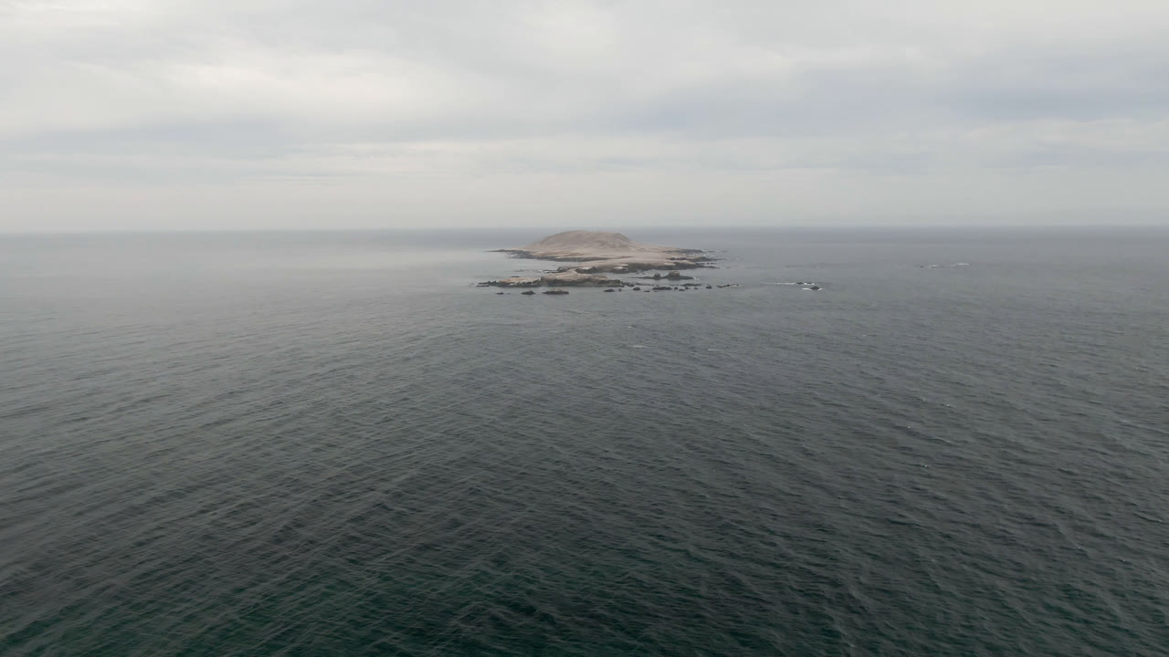 Second frame holds the Bahia Ascuncion island slightly clearer against the horizon, with textured ocean surface below and no visible people.