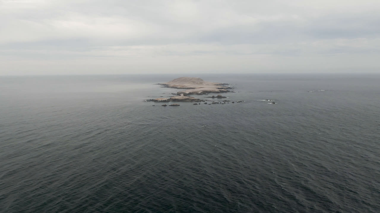 Opening frame from Bahia Ascuncion, Baja California Sur, Mexico, with dark rippled water leading to a low rocky island near the horizon and no visible people.