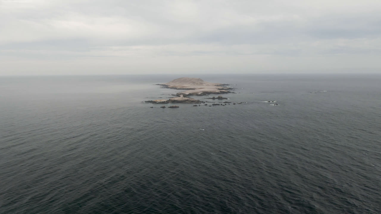 At 0:02 in Bahia Ascuncion, the distant island remains near the horizon with small rock outcrops around it, broad dark water below, and no visible people.