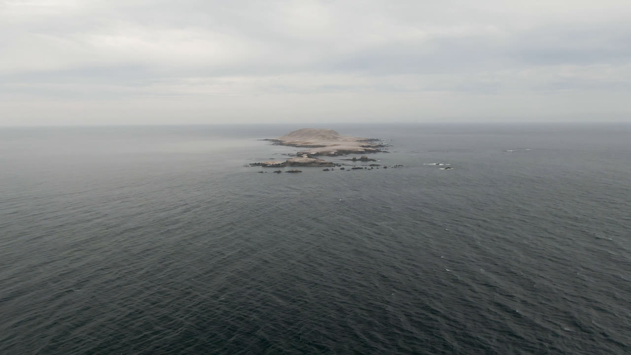 Small rocky island and offshore rocks seen across open water