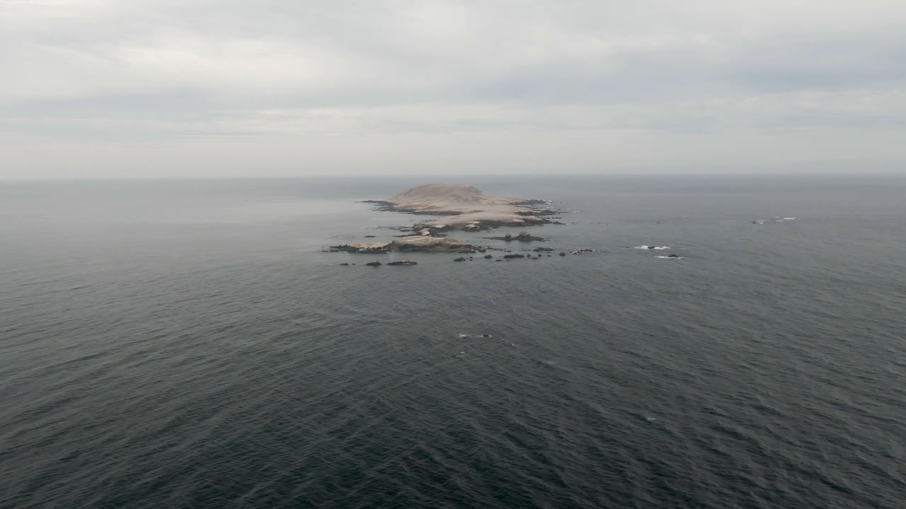 Distant rocky island centered across open ocean