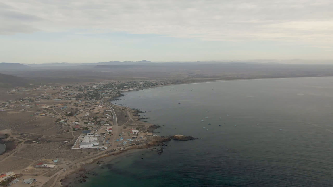 Wide aerial of Bahia Ascuncion coastline with town blocks and calm water.