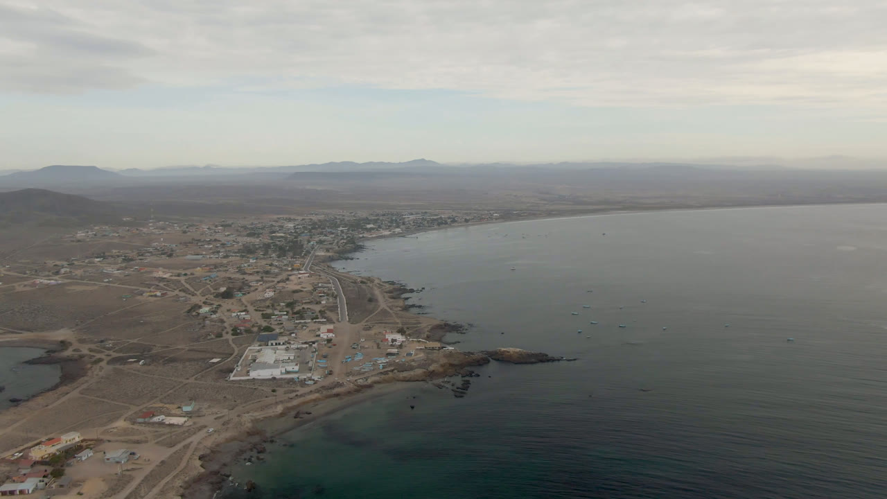 Aerial view of a coastal town beside a wide body of water under clouds.