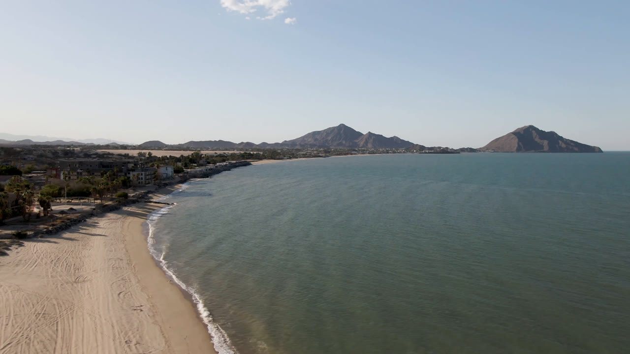 Aerial view of sandy beach, ocean water, and distant mountains
