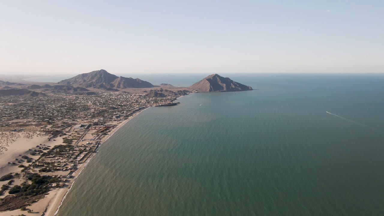 Aerial frame over San Felipe, B.C., Mexico, showing the shoreline curving from the lower left, shallow water in the center, clustered buildings inland, and no visible people.