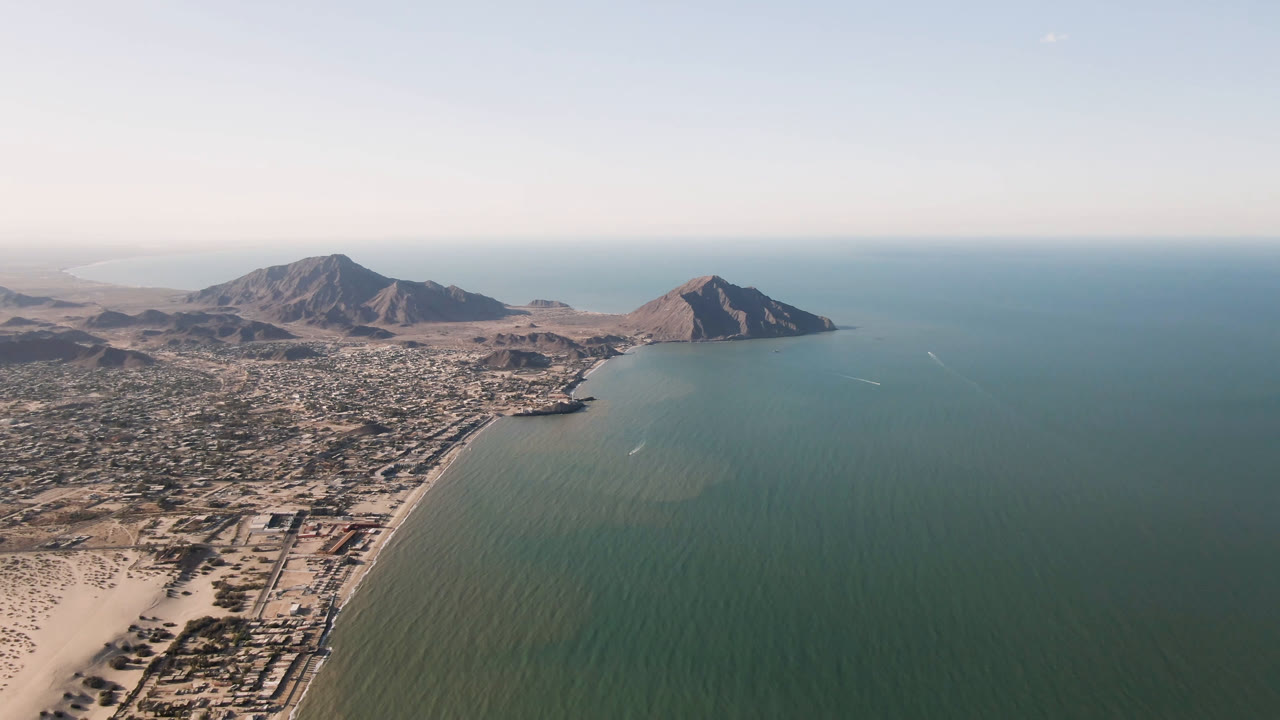 Aerial view of San Felipe, Baja California, Mexico, showing the beach and town grid beside broad water, with rugged mountains across the horizon and no visible people.