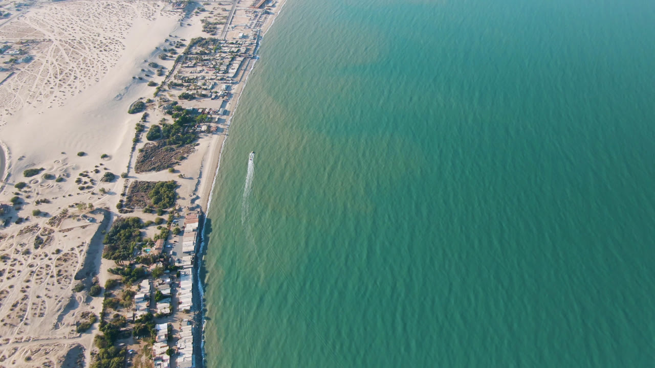 Aerial view of sandy coast, shoreline buildings, and blue ocean