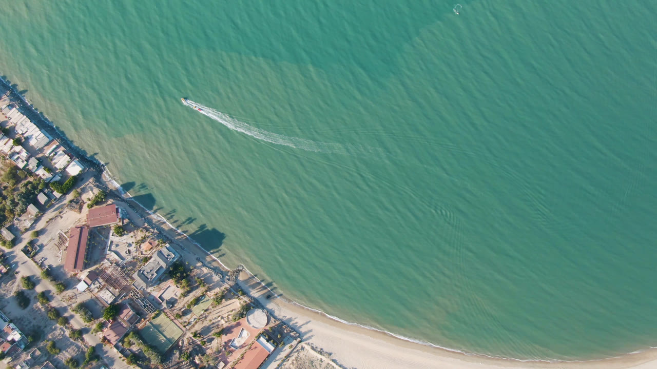 Overhead beach shoreline with a small boat on green water