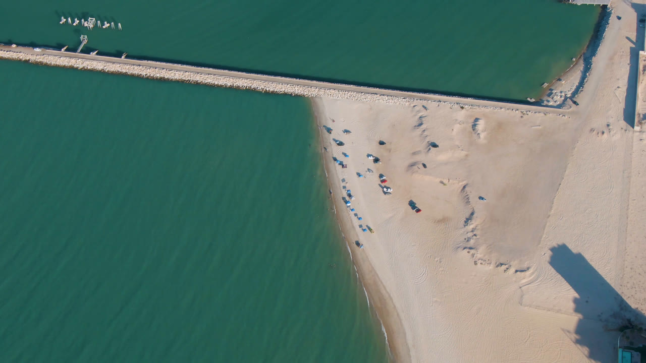 Overhead beach and green water beside a straight pier structure.