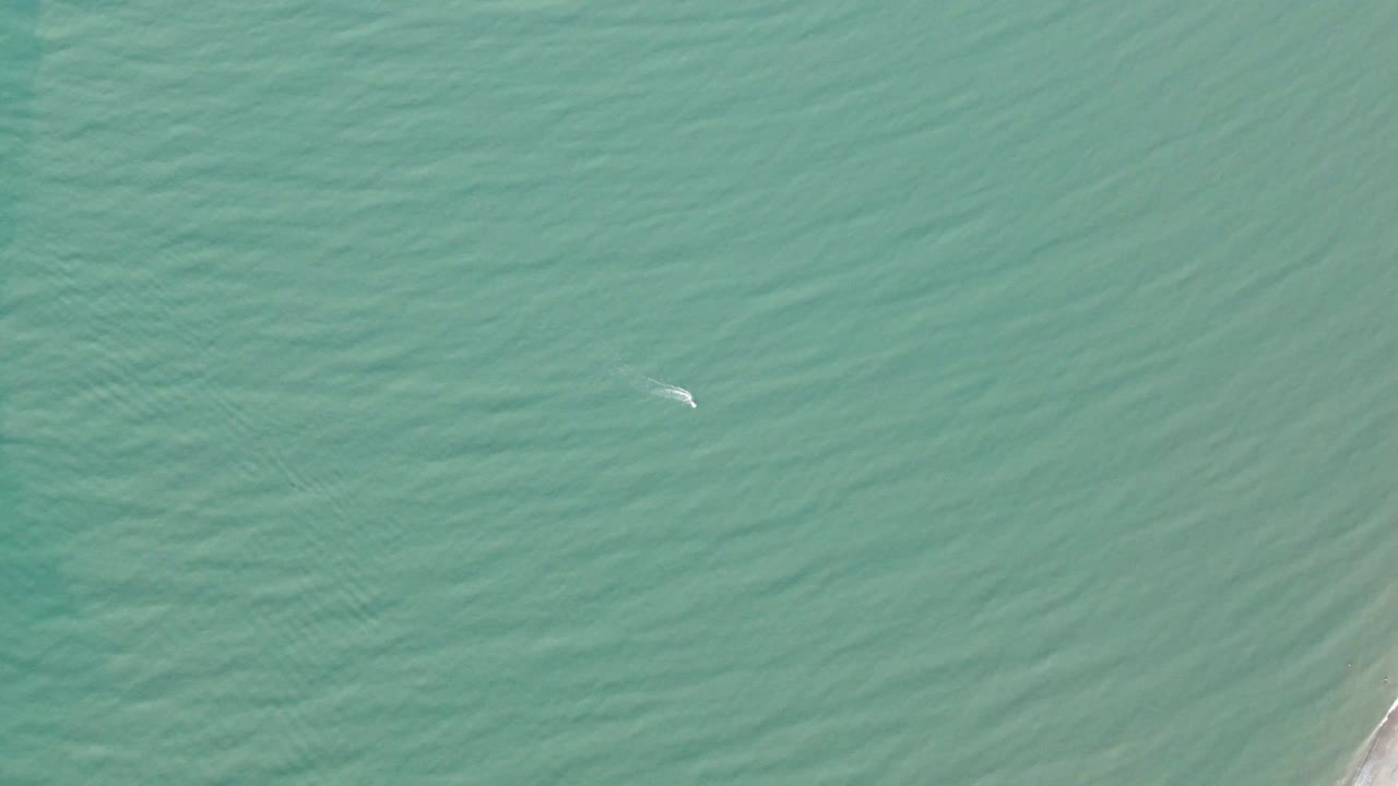 Aerial ocean view in San Felipe, BC, Mexico, with rippled green-blue water filling the frame, a small white kite slightly left of center, and no visible people or boats.