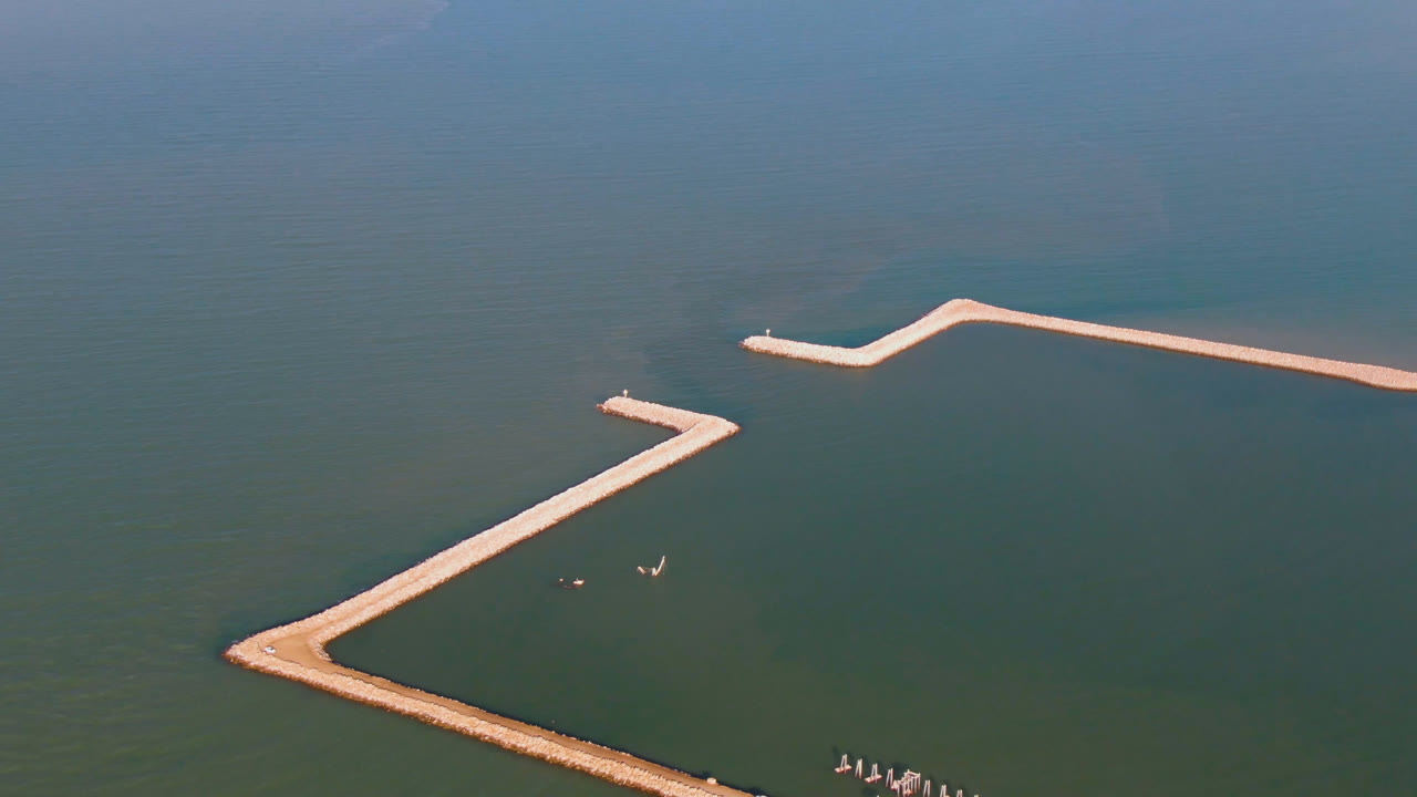 Aerial view in San Felipe with the long pale dock or breakwater shifted slightly across the frame, small objects on the water, and no visible people.
