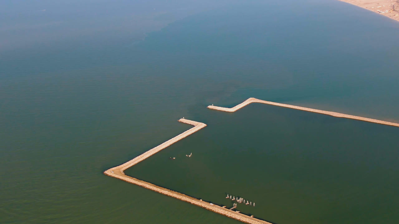 Aerial frame over San Felipe, Baja California, Mexico, showing green-blue water crossed by pale angular pier structures, with no visible people.