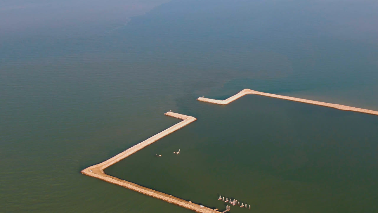 High aerial view of calm water and two pale pier lines.