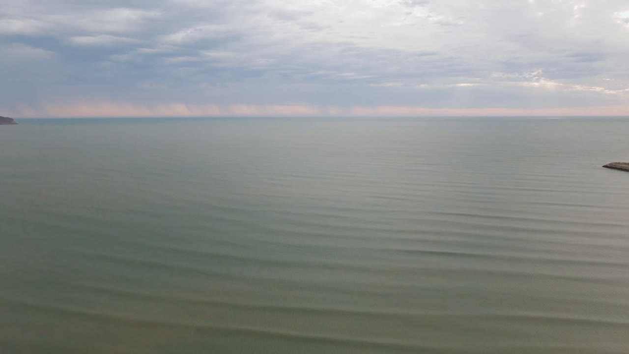 Wide ocean surface beneath layered clouds and a distant horizon.