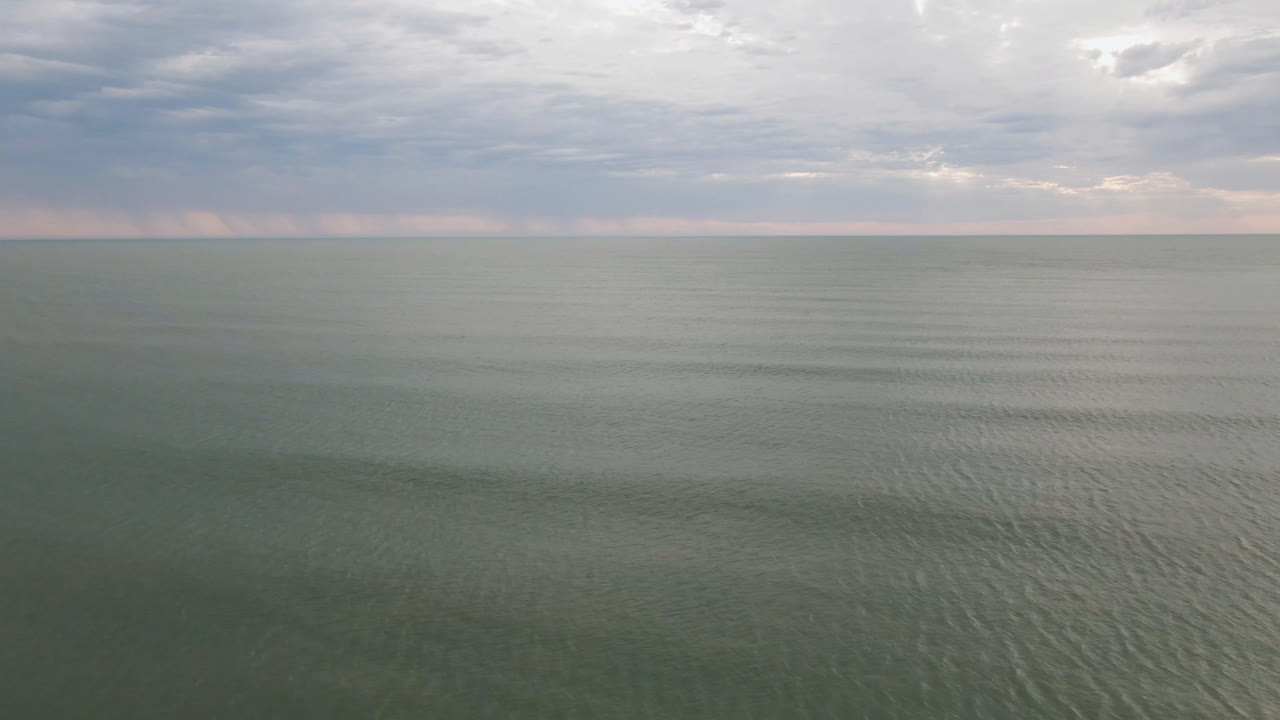 Wide elevated view over muted green-gray water near San Felipe, Mexico, with a flat horizon, cloudy sky, and no visible people.