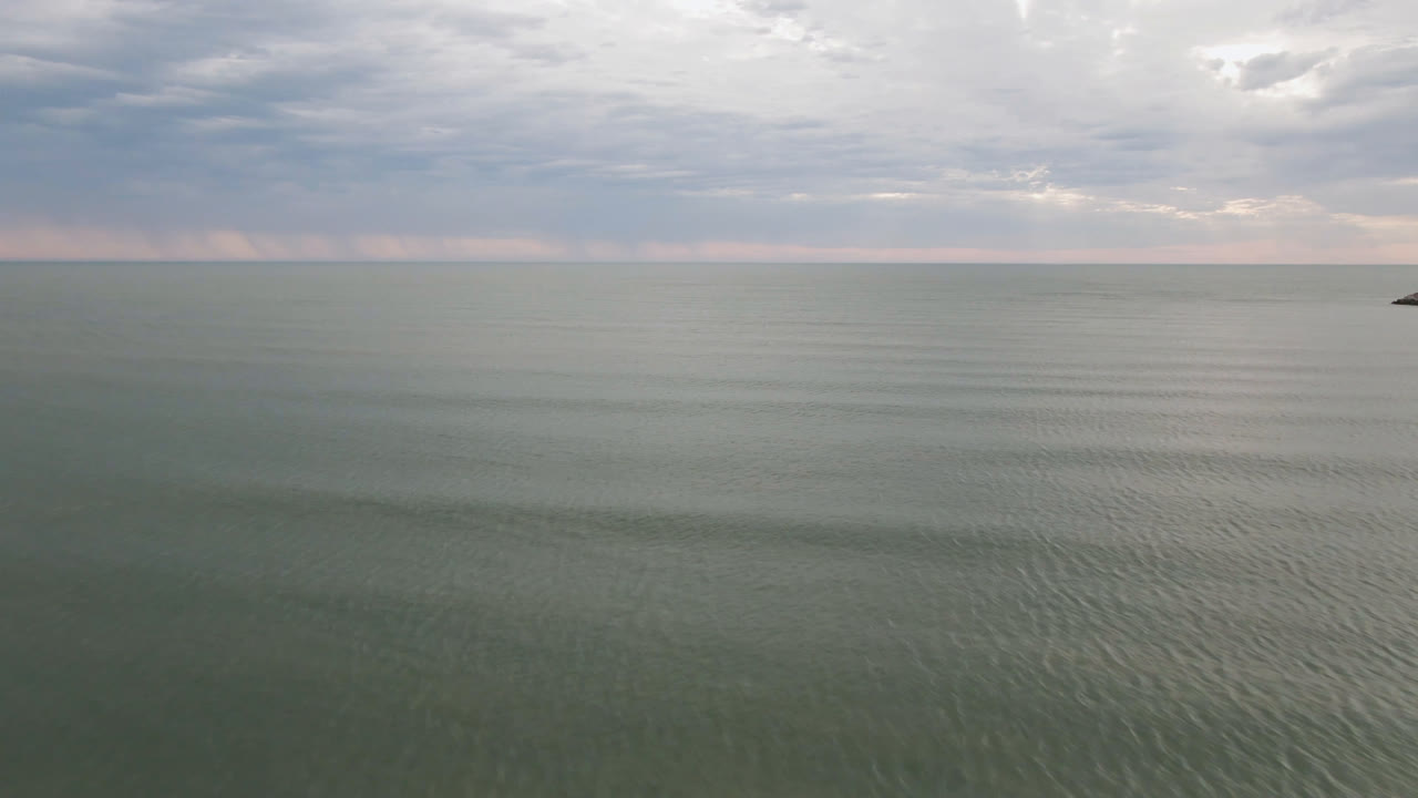Wide view of San Felipe water under layered gray clouds, with a small dark boat near the horizon and no visible people.