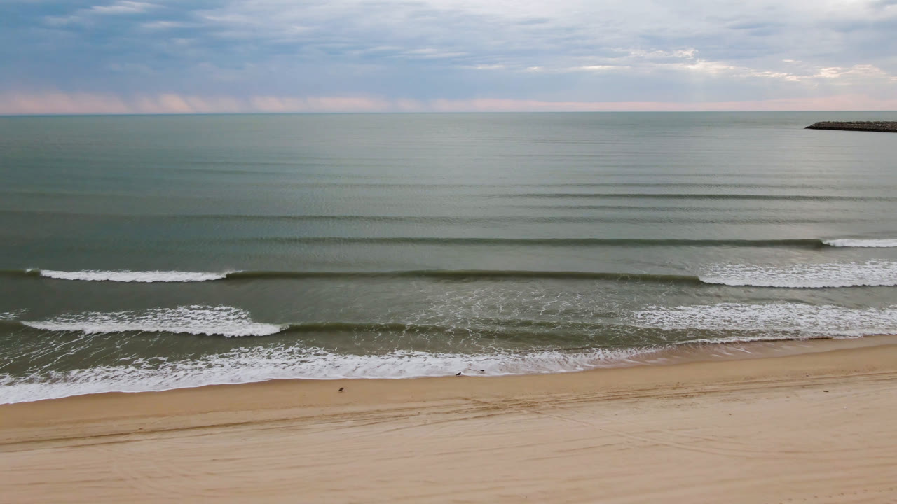 At 0:01, the San Felipe shoreline shows a broader band of foamy surf over tan sand, green-blue water beyond it, a flat horizon, and no visible people.