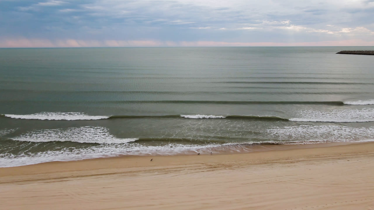 Empty beach and calm ocean under a clouded sky