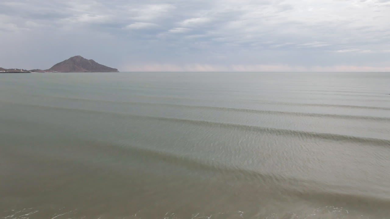 Open water, low waves, and distant mountain under clouds.