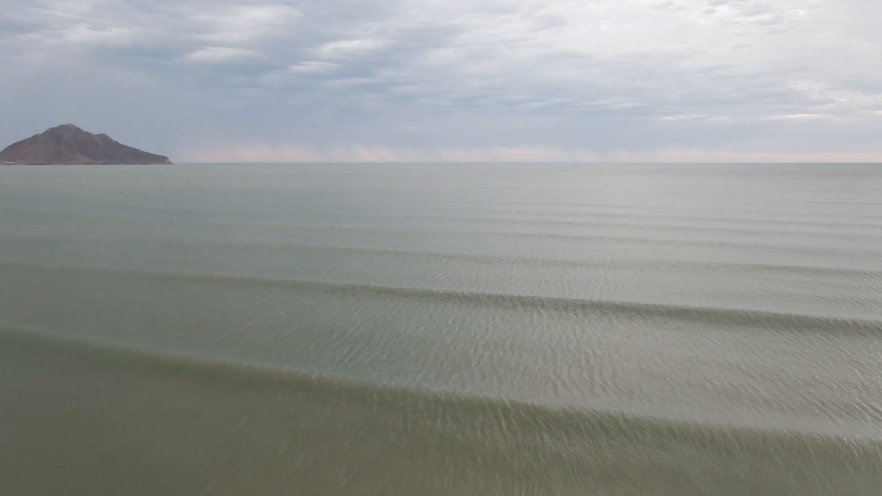 Wide shallow water view with distant mountain and cloudy sky