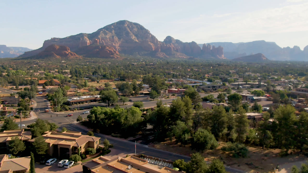 Wide aerial view of a town below red rock mountains
