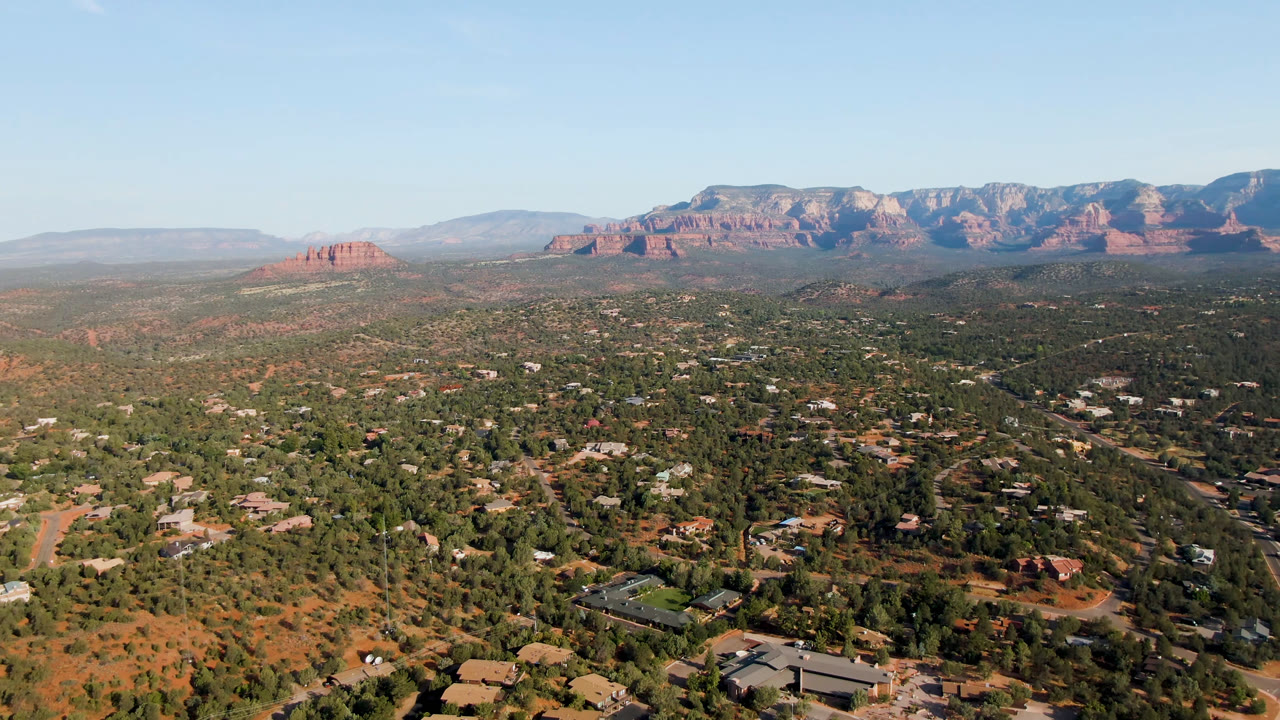 Wide Sedona aerial with desert vegetation and red rock horizon.