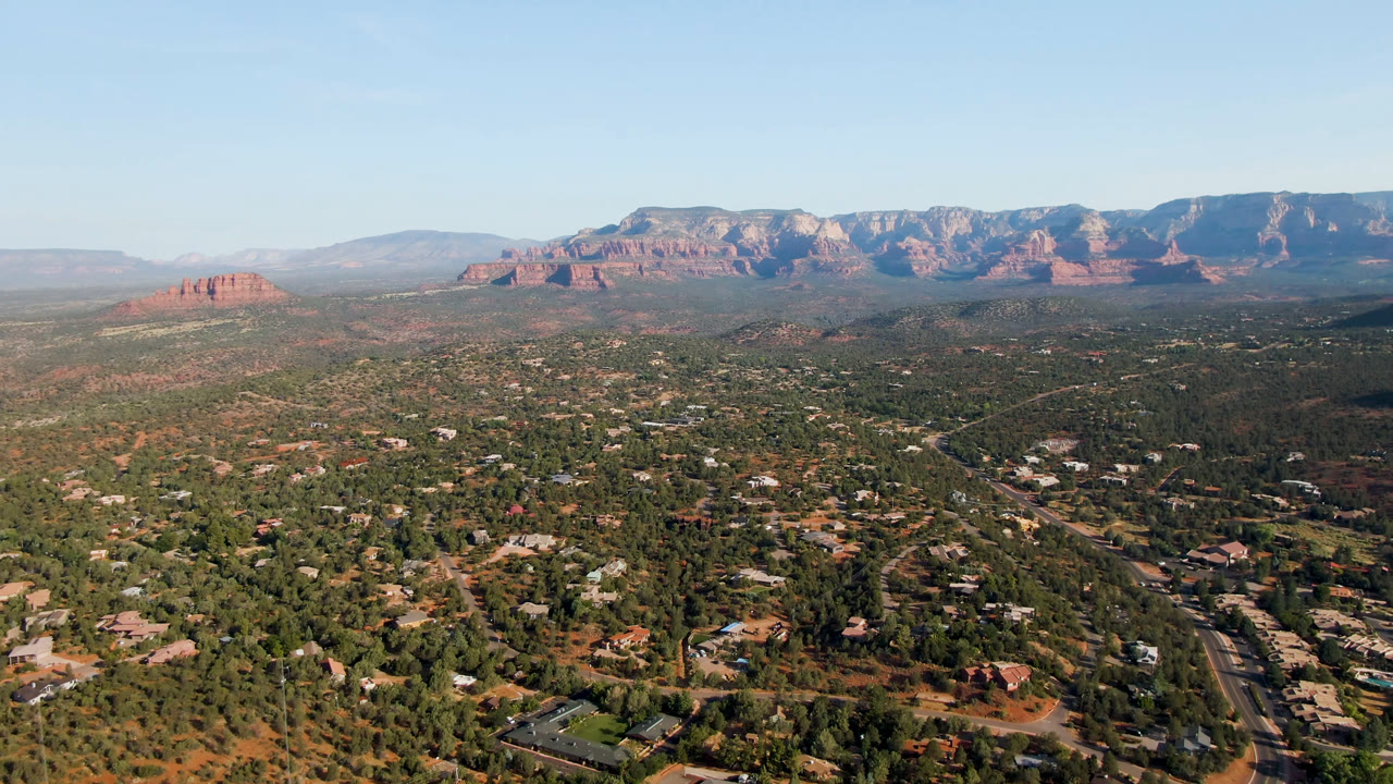 Wide aerial view of Sedona with red rock mountains and desert town below