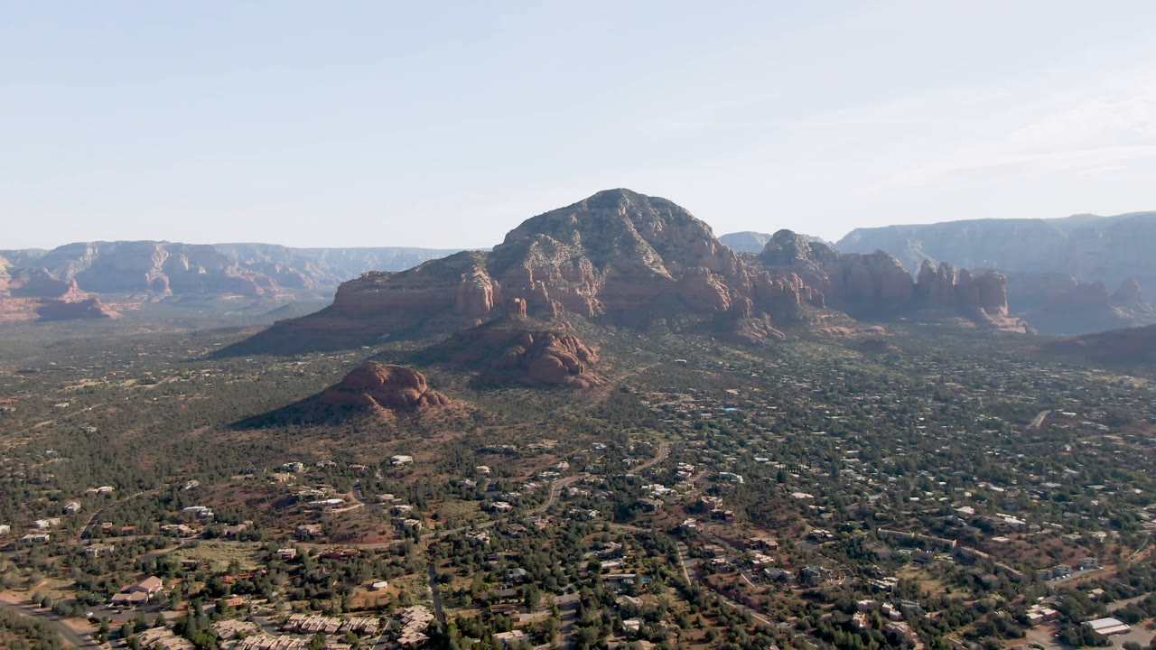 Wide aerial view of red rock mountains above a desert town