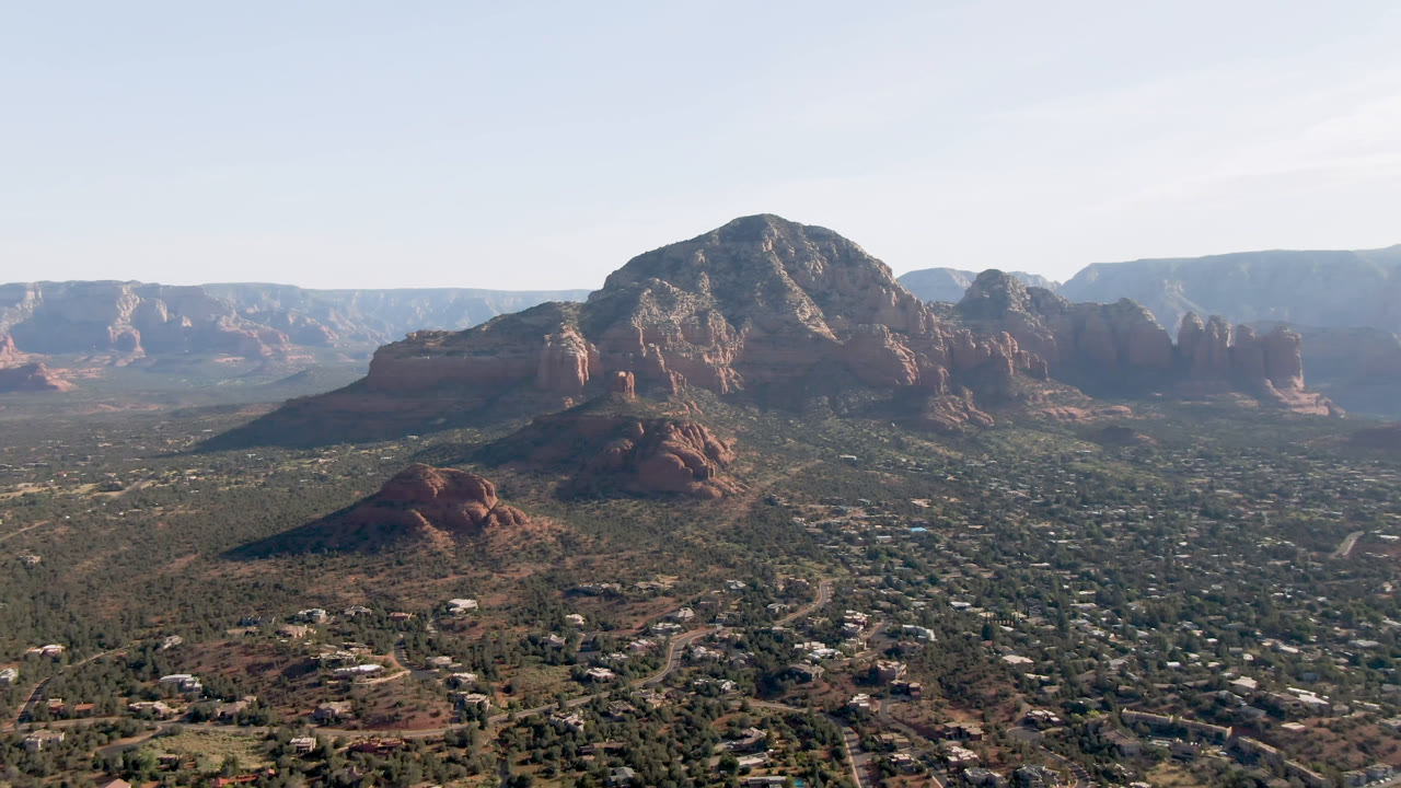 Wide aerial view of red rock mountains above a desert town