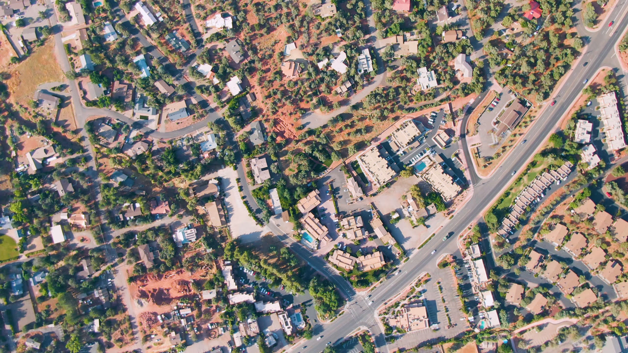 Overhead aerial view of roads, buildings, trees, and tan lots.