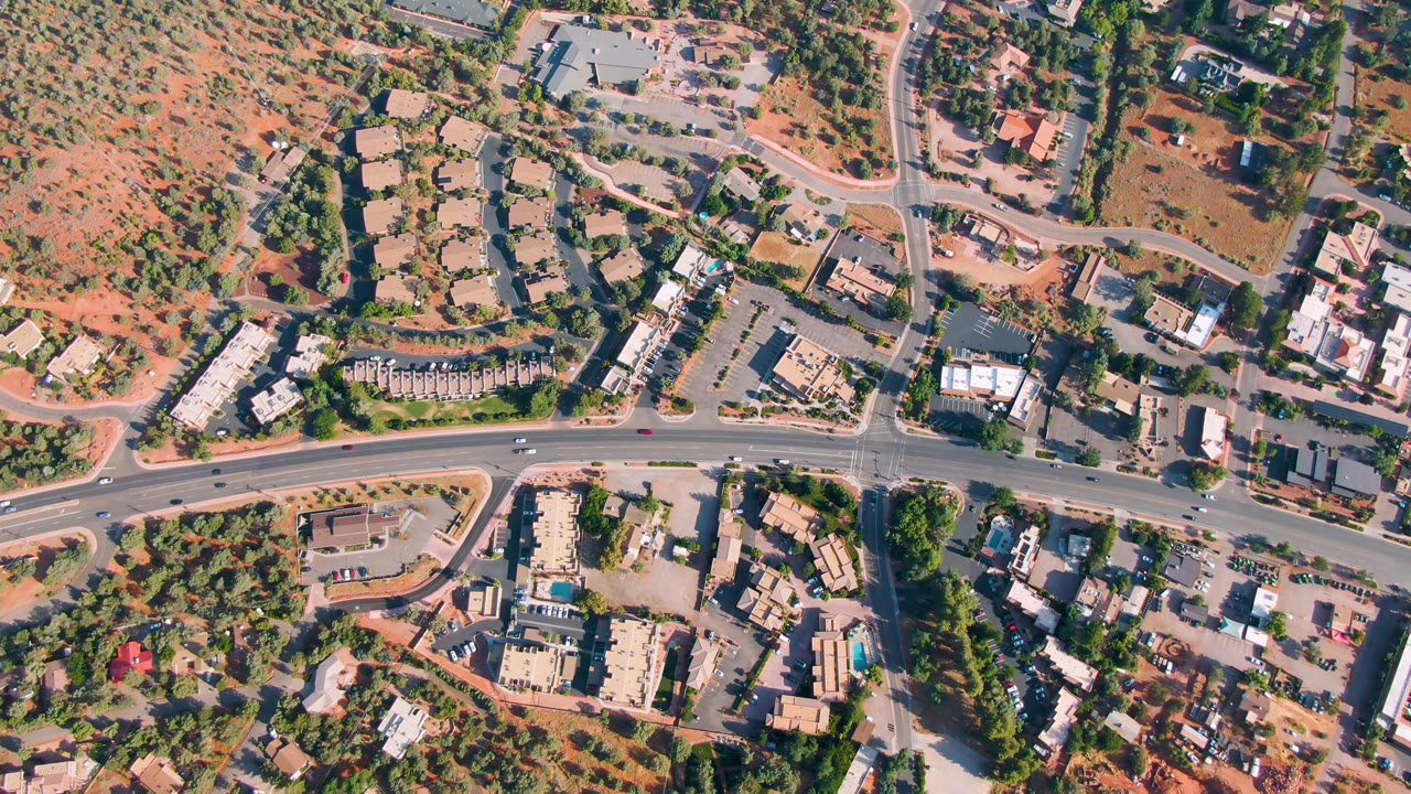 Overhead road intersection with buildings, trees, and red desert terrain.