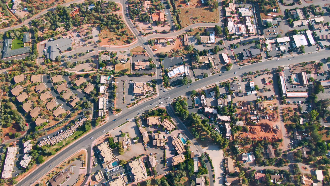 Overhead view of roads, buildings, trees, and red dirt lots.