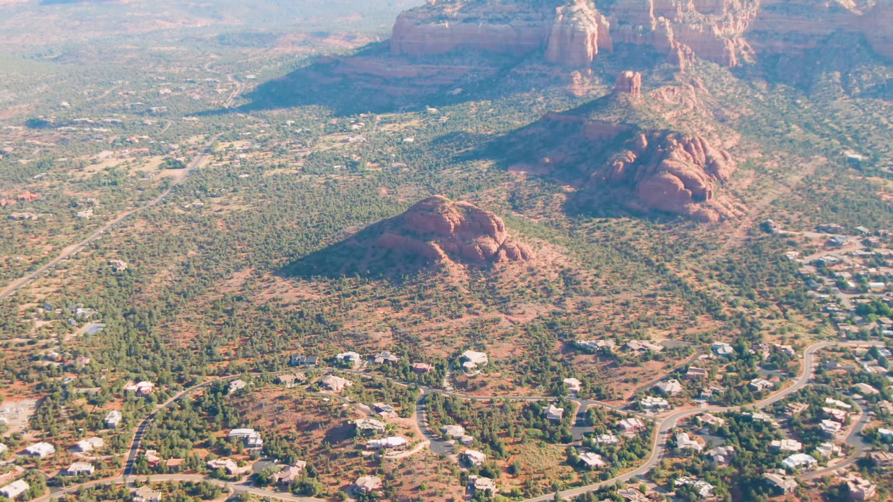 Sedona aerial landscape with a red hill, roads, buildings, and cliffs.