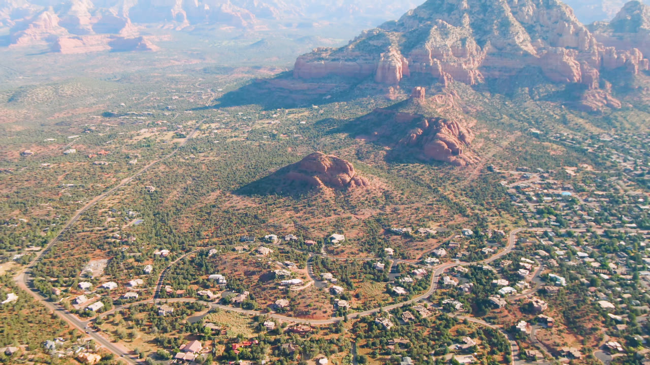 Aerial view of a desert town below red rock mountains