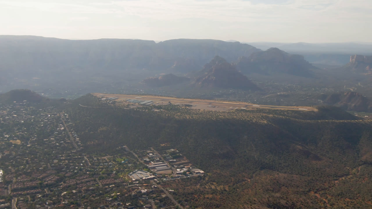 Wide aerial view of a desert town below mesas and buttes