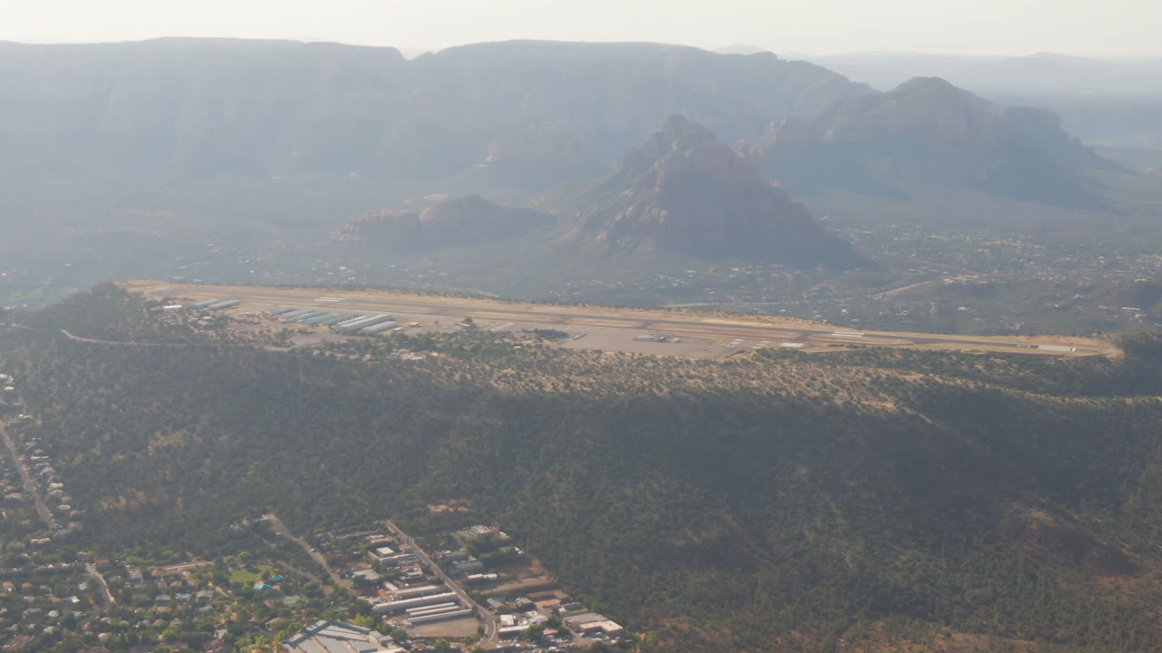 Aerial view of a small town below red rock mountains and mesas.