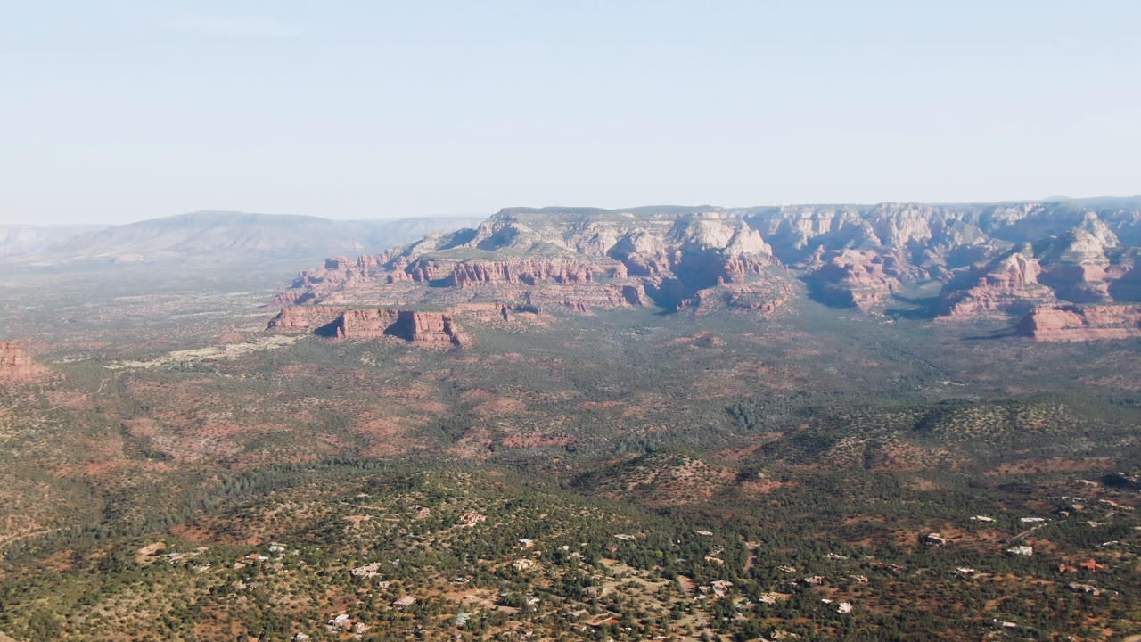 Wide aerial valley with red rock mountains and desert homes