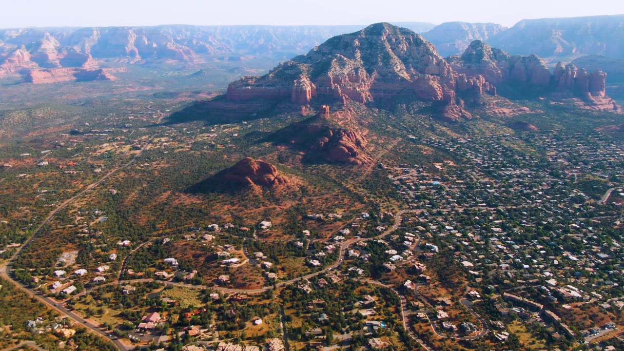 Wide aerial view of Sedona town below red rock mountains