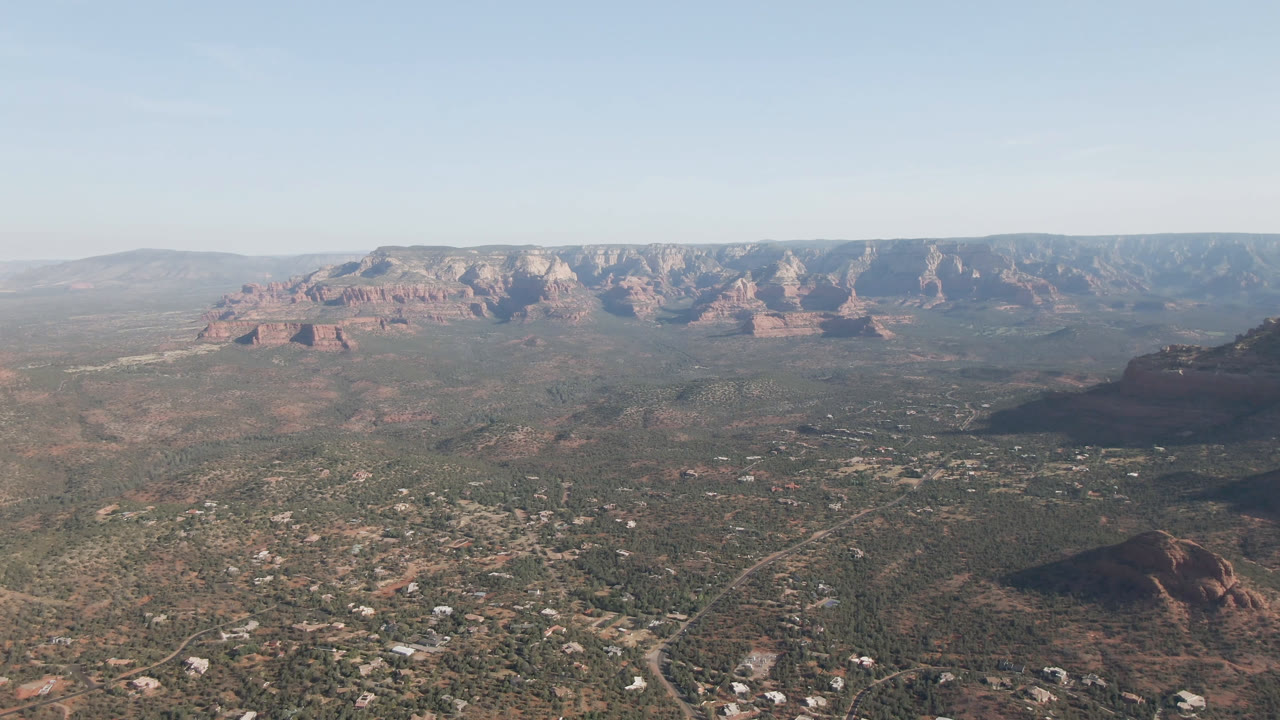 Second frame shows the Sedona, Arizona valley from above, with residential roads in the lower frame, red rock buttes across the middle distance, a long ridge behind them, and no visible people.