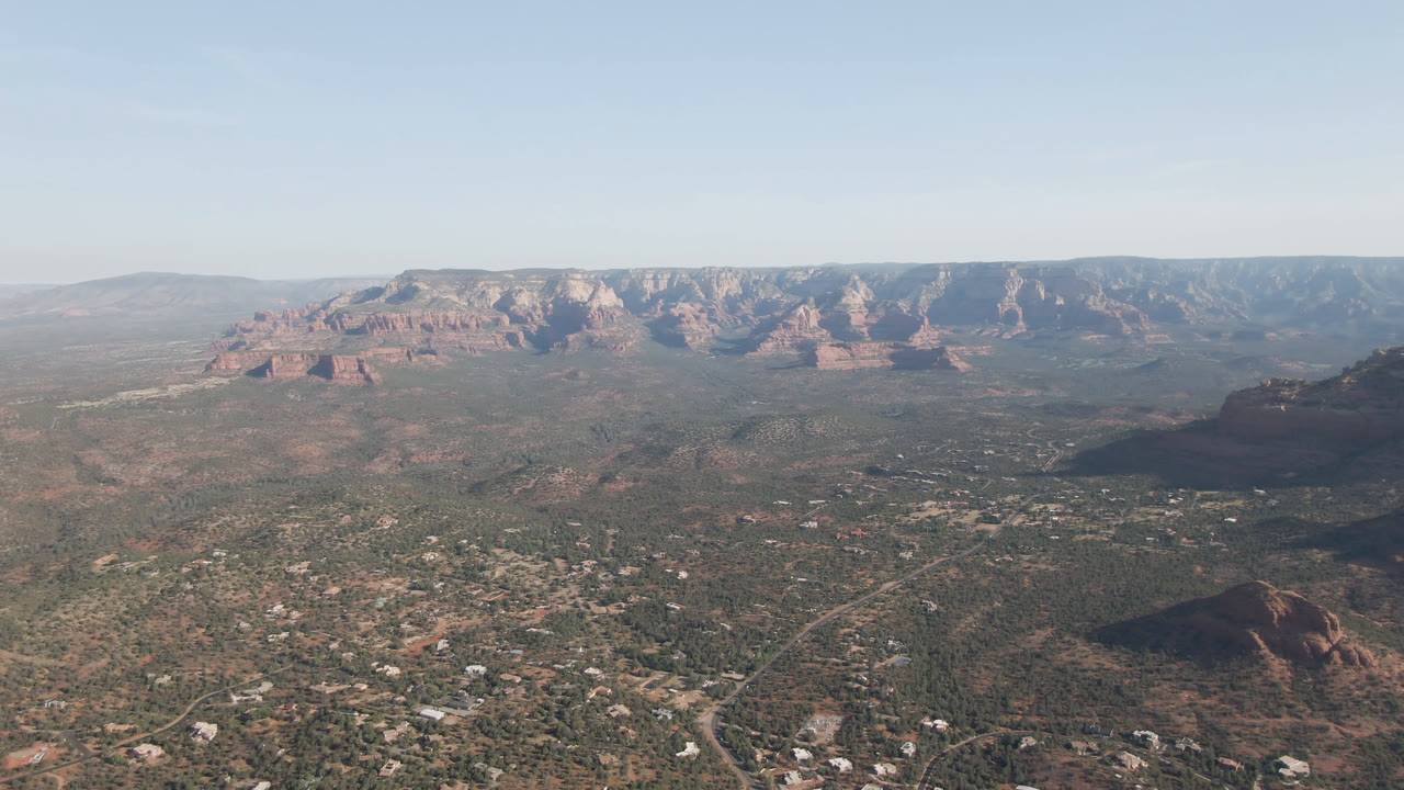 High desert aerial with Sedona buildings, roads, and red rock mountains.