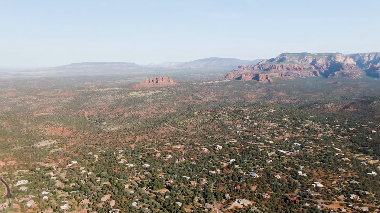 High aerial view over a desert town with red rock formations and blue sky.