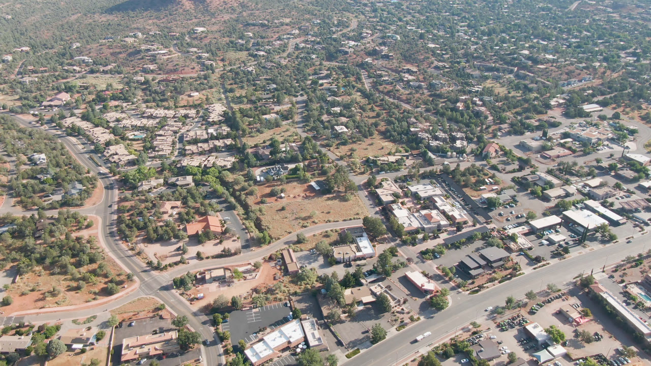 Overhead view of a Sedona neighborhood with roads, trees, cars, and buildings.